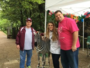 people posing for picture around zebra