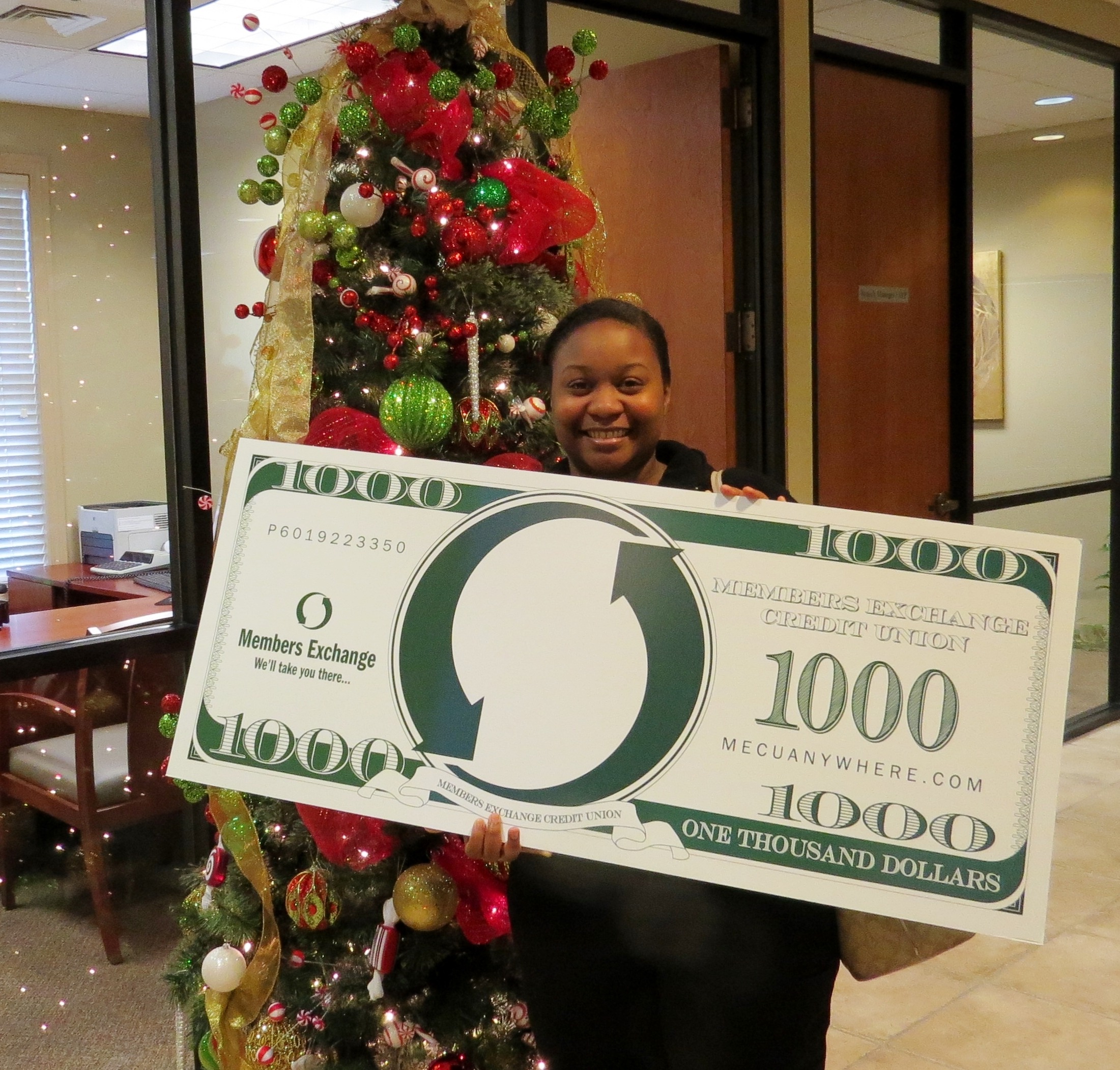 Woman holding a novelty thousand dollar bill with a Members Exchange logo.