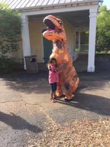 Child hugs dinosaur mascot at CU at the Zoo.