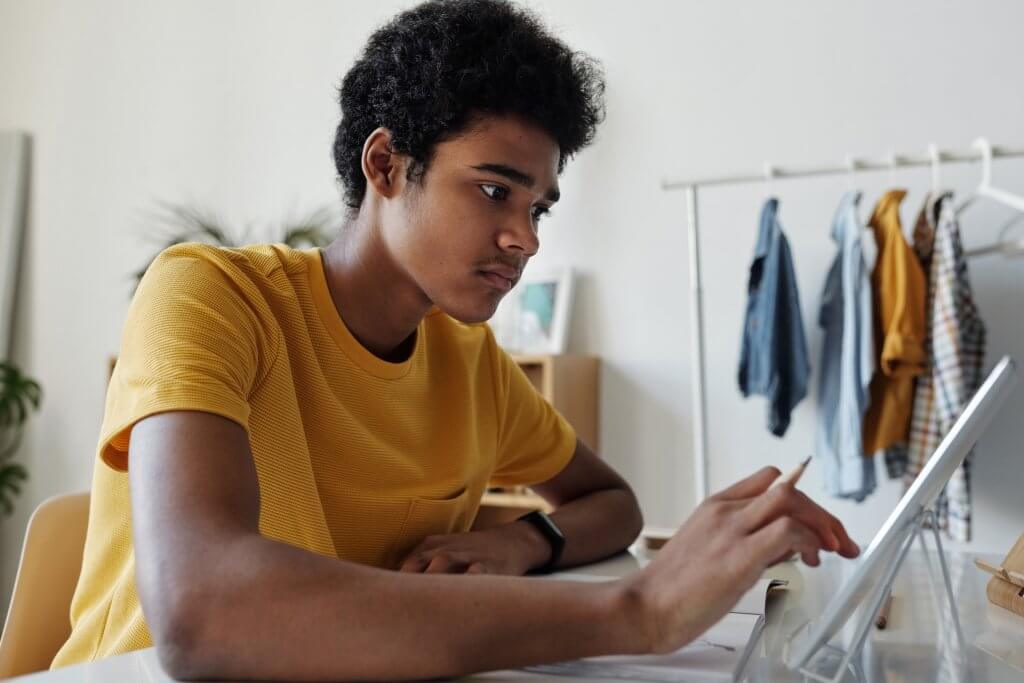 Young man working on a tablet with pencil in hand.