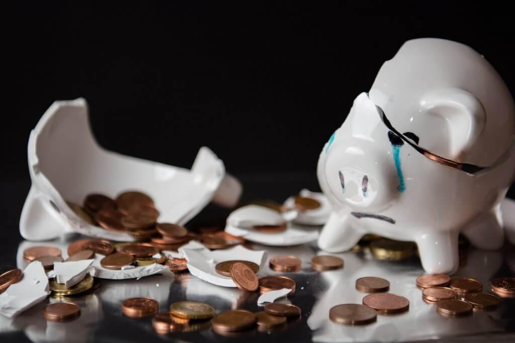 Broken piggy bank with coins spilling out.